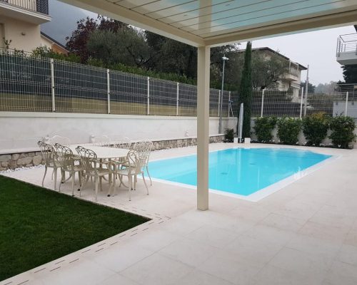 Bordo piscina in marmo sotto pergolato